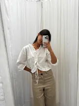 Blusa color blanco de lino, con mangas 3/4 y volados en el frente. Se ata con lazos en el centro.