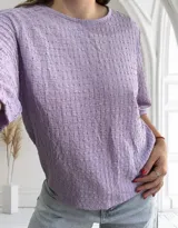 Blusa de manga corta color lila con cuello redondo y textura tejida en relieve con patrón de pequeños cuadros.