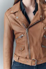 Campera de cuero ovino negra, estilo rocker, con cuello con solapas, cierre cruzado, cinturón ajustable en la cintura, charreteras en los hombros y múltiples cierres metálicos decorativos. Forro de poliéster.