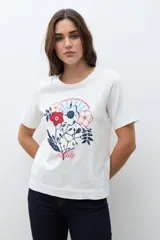 Remera blanca de manga corta con cuello redondo y un estampado frontal de flores y follaje en tonos rojo, azul marino y blanco.