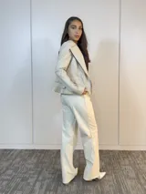 Chaqueta color beige de cuero sintético con cierre lateral y volados en la espalda baja.