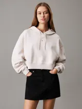 Buzo con capucha Calvin Klein color crema, de corte boxy y largo cropped. Presenta logo pequeño bordado en el pecho, cordones ajustables en la capucha y puños y bajo acanalados.