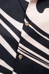 Camisa de manga corta con cuello tipo camp, con estampado abstracto en tonos beige y negro.