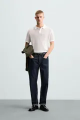 Polo blanco de punto tejido con estructura calada, corte regular fit, cuello solapa con abertura frontal y manga corta.