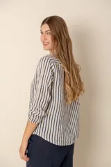 Camisa de lino a rayas verticales azules y blancas, con cuello mao, manga larga con puño elástico y cierre frontal con botones.