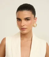 Caravanas de botón con diseño redondo y acabado en baño de oro batido, con una perla central de gran tamaño. Están confeccionadas en metal reciclado.