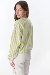 Buzo de poliéster a rayas verticales verdes y blancas en la parte superior y beige y blancas en la parte inferior, con cuello, puños y ruedo blancos. Estampado frontal con la frase "The Flowers Club" y la palabra "Petra".
