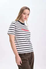 Remera de manga corta con cuello redondo y estampado a rayas horizontales en blanco y negro. Tiene la palabra 'Amour' estampada en rojo.