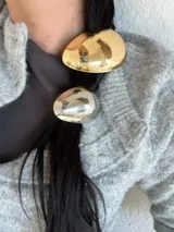 Colita de pelo dorada con aplique metálico ovalado.