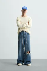 Jersey color crudo de algodón con textura, corte relaxed fit, cuello redondo y manga larga. Acabados en rib con detalle de vuelta.