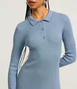 Vestido corto negro de punto con cuello polo, manga larga y botones en el escote.