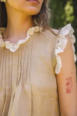 Blusa de lino color blanco, sin mangas, con cuello fruncido y volados de encaje en las sisas. Presenta pinzas frontales y un diseño de calce holgado de estilo romántico.