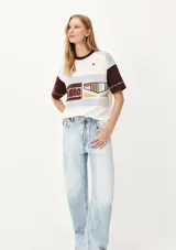 Camiseta de mangas cortas con cuello redondo y corte amplio. Presenta un diseño con bloques de color y estampados con motivos náuticos y geométricos.