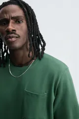 Camiseta verde oscuro de corte relaxed fit, cuello redondo, manga corta y bolsillo plastrón en el pecho.