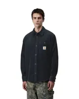 Camisa de manga larga confeccionada en pana de color azul marino, con cuello clásico y cierre frontal de botones. Presenta un bolsillo de parche en el pecho con la etiqueta de la marca Carhartt.