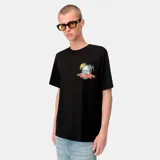 Camiseta negra de corte regular con un pequeño parche bordado en el pecho izquierdo. El parche presenta un diseño de paisaje tropical con palmeras y un horizonte marino, enmarcado por una cinta roja con texto.