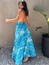 Vestido largo de tela fluida, color azul vibrante con estampado tie-dye en tonos beige/crudo. Diseño halter con tirantes finos ajustables y cintura marcada con lazo.