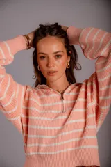 Sweater de punto color beige con rayas horizontales blancas, cuello polo con cierre de cremallera y mangas largas.