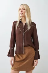 Camisa de vestir marrón con cuello clásico, cierre frontal con botones, mangas largas con puños abotonados y detalles de pespuntes blancos en cuello, solapa y canesú.