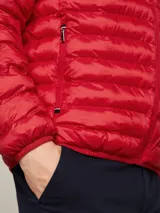 Campera acolchada roja de poliéster reciclado, con cuello alto, cierre de cremallera, bolsillos laterales y logo de Tommy Hilfiger bordado en el pecho.