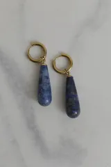 Par de aros colgantes con argolla dorada de acero quirúrgico hipoalergénico y dije en forma de gota de piedra natural blanca.