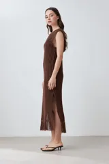 Vestido marrón de tejido calado, corte recto, largo midi, sin mangas y con flecos en el ruedo.