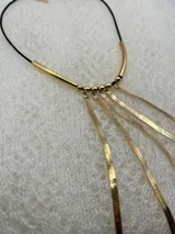 Collar dorado con colgantes de cadena fina y cordón negro.