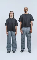 Pantalón cargo gris de corte oversize, confeccionado en tejido técnico de poliéster. Cuenta con cintura elástica, múltiples bolsillos y detalles reflectivos.
