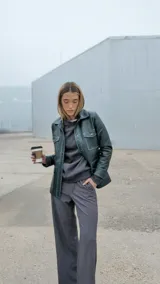 Chaqueta verde gastado de cuero ovino, con cuello clásico, cierre frontal con botones, bolsillos con solapa en el pecho y corte recto.