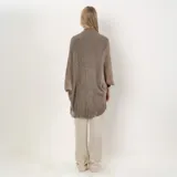 Poncho color marrón claro con flecos en el borde inferior.