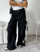 Pantalón cargo negro de denim rígido, corte wide leg, con bolsillos laterales y detalles de tiras con hebillas en los laterales.