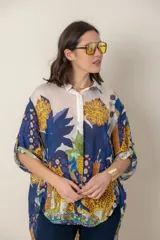 Camisa italiana de viscosa estampada con diseño abstracto en tonos azul, amarillo y verde sobre fondo natural, de corte irregular y mangas 3/4.
