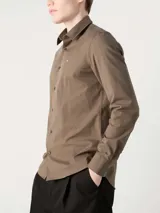 Camisa de vestir color marrón, corte slim, de popelín de algodón elástico, con cuello clásico, cierre frontal con botones y logo "ck" bordado en el pecho.