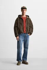 Cazadora relaxed fit confeccionada en tejido de algodón denim color marrón. Cuello con capucha ajustable y manga larga. Bolsillos frontales tipo canguro. Acabados con elástico. Efecto lavado. Cierre frontal de cremallera.
