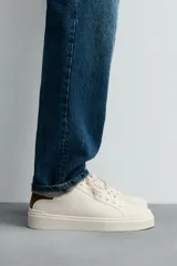 Zapatillas deportivas blancas de caña baja con detalle de color gris en el talón y suela con volumen.