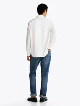 Camisa blanca de sarga de puro algodón teñido en prenda, con cuello con botones, bolsillo de parche en el pecho y puños redondeados con botón.