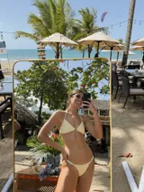 Top de bikini negro con textura, corte triangular, breteles finos y argolla decorativa de resina en el centro.