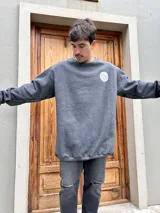Buzo gris con cuello redondo y logo estampado en el pecho. Corte oversize.