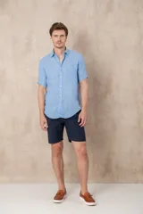 Camisa celeste de lino con manga corta, cuello clásico y corte recto.
