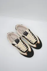 Zapatillas urbanas de cuero color beige con puntera y cordones marrones. Presentan un panel de animal print en el talón y suela de goma color caramelo.