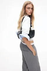Pantalón gris de sarga con cintura elástica fruncida y cordón ajustable. Piernas amplias con pliegues cosidos, bolsillos laterales discretos y bolsillos decorativos atrás.