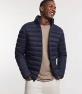 Campera puffer ultraligera color beige, con cuello alto, cierre por cremallera y bolsillos con cremallera. Incluye bolso de almacenamiento.