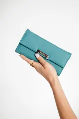 Monedero color turquesa con interior para tarjetas y billetes, broche imán y bolsillo interno con cierre.
