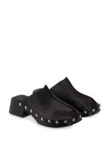 Zueco de piel color negro con plataforma de madera y detalles de tachuelas plateadas.