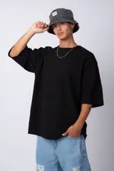 Remera verde militar de corte oversize, confeccionada en algodón 100% con cuello redondo y manga corta. Presenta un pequeño logo estampado en la parte superior de la espalda.