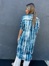 Sobrecamisa o vestido largo con estampado tie-dye en tonos azules y blancos, con cuello camisero, mangas cortas y cierre frontal con botones.