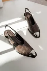 Zapato tipo slingback color marrón con estampado de cocodrilo, punta afilada con detalle metálico plateado y tira trasera elástica.
