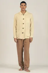 Campera color crema estilo sobre camisa hecha en lino premium con cuello clásico, cierre con botones marrones, dos bolsillos de parche inferiores y un bolsillo de parche superior.