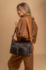 Bandolera de tafeta impermeable, liviana, con dos compartimientos principales, dos bolsillos con cierre y correa regulable con hebilla.