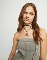 Colgante largo con cordón negro efecto seda y dije de corazón dorado con cristal negro en el centro.